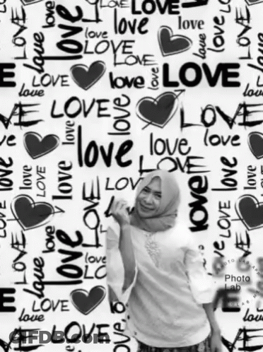A Woman Stands In Front Of A Wall That Has The Word Love Written On It GIF