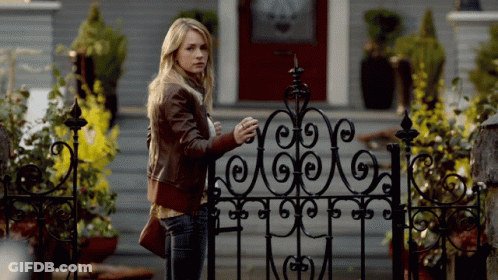 Woman Standing In Front Of Wrought Iron Gate GIF
