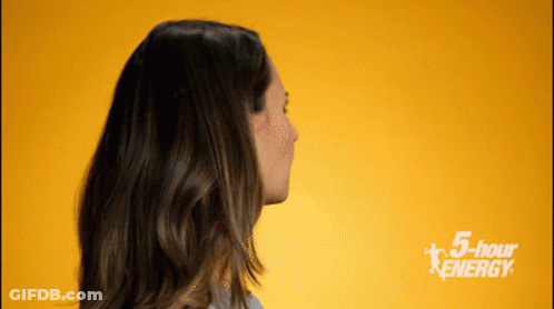A Woman Stands In Front Of A Yellow Background With The Words 5 Hour Energy On It GIF