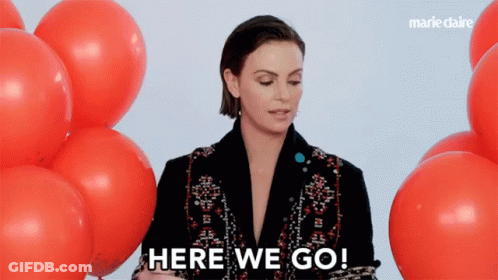 A Woman Stands In Front Of Red Balloons And Says " Here We Go " GIF