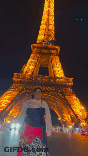 A Woman Stands In Front Of The Eiffel Tower GIF