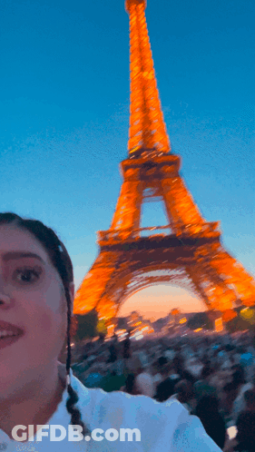 A Woman Stands In Front Of The Eiffel Tower In Paris GIF