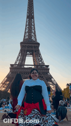 A Woman Stands In Front Of The Eiffel Tower Wearing A Leopard Print Skirt GIF