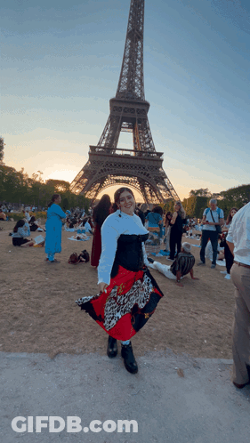 A Woman Stands In Front Of The Eiffel Tower Wearing A Leopard Print Skirt GIF