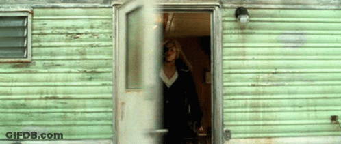 A Woman Stands In The Doorway Of A Green Trailer GIF