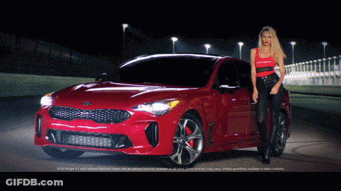 A Woman Stands Next To A Red Kia Stinger GIF