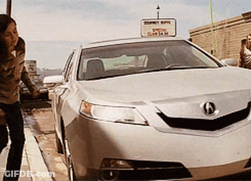A Woman Stands Next To A Silver Car With A Sign Above It That Says ' Acura ' GIF
