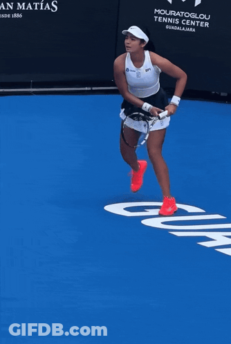A Woman Stands On A Blue Tennis Court In Front Of A Sign That Says Casa San Matos GIF