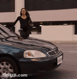 A Woman Stands On The Hood Of A Blue Honda GIF