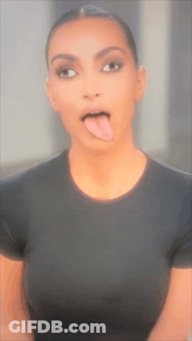 A Woman Sticking Her Tongue Out While Wearing A Black Shirt GIF