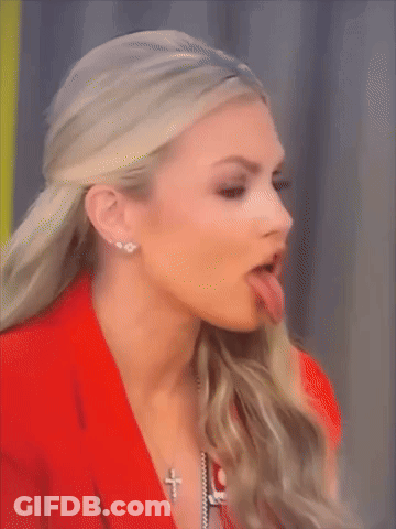 A Woman Sticking Her Tongue Out While Wearing A Cross Necklace GIF
