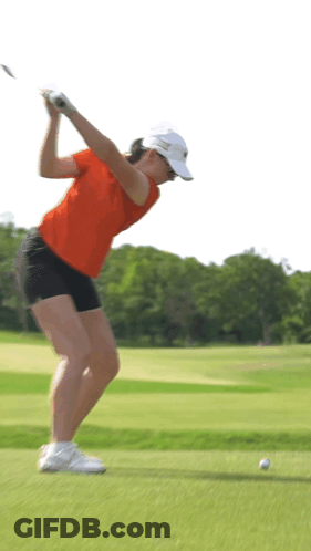 A Woman Swinging A Golf Club On A Golf Course GIF