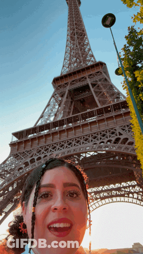 A Woman Taking A Picture In Front Of The Eiffel Tower GIF