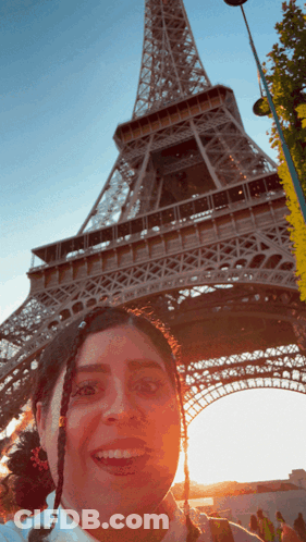 A Woman Taking A Picture In Front Of The Eiffel Tower GIF
