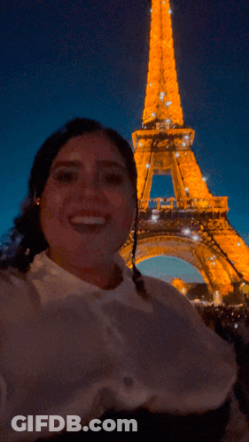 A Woman Taking A Picture In Front Of The Eiffel Tower GIF