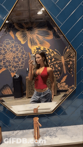 A Woman Taking A Picture Of Herself In A Mirror GIF