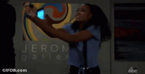 A Woman Taking A Picture Of Herself In Front Of A Sign That Says Jerom Galler GIF