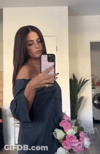 A Woman Taking A Picture Of Herself In The Mirror GIF