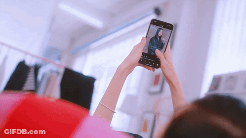 A Woman Taking A Picture Of Herself With A Cell Phone GIF