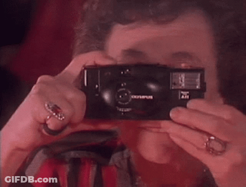 A Woman Taking A Picture With An Olympus Camera GIF