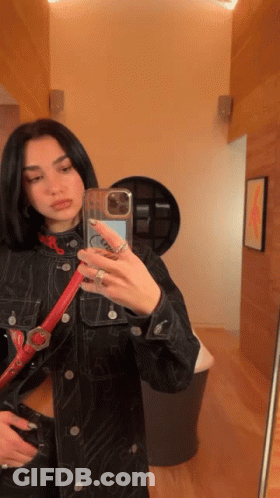 A Woman Taking A Selfie In Front Of A Mirror GIF