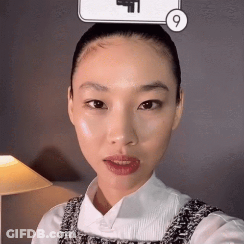 A Woman Taking A Selfie In Front Of A Sign That Has The Number 9 On It GIF