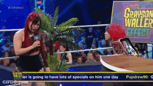 A Woman Talking Into A Microphone With A Sign That Says Grayson Waller Effect GIF