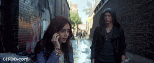A Woman Talking On A Cell Phone While A Man Stands Behind Her GIF