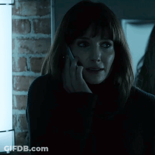 A Woman Talking On A Cell Phone With A Brick Wall In The Background GIF