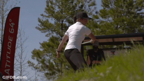 A Woman Throws A Frisbee In Front Of A Latitude 64 Banner GIF