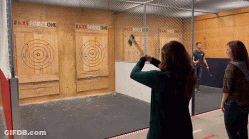 A Woman Throws An Axe At A Target That Says Axeforceone GIF
