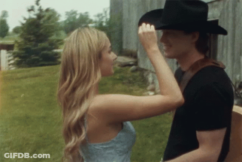 A Woman Touches A Man 'S Forehead While He Holds A Guitar GIF