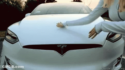 A Woman Touches The Hood Of A White Tesla GIF