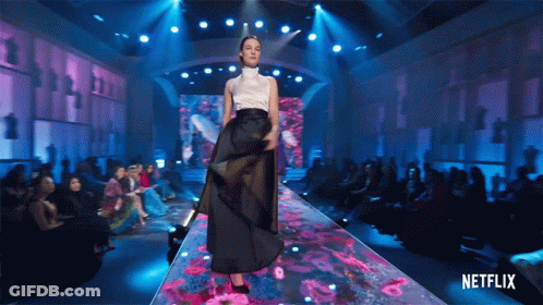 A Woman Walking Down A Runway With A Netflix Logo In The Background GIF