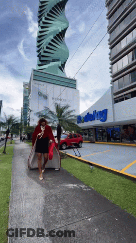 A Woman Walking Down A Sidewalk In Front Of A Store That Says Redelag GIF