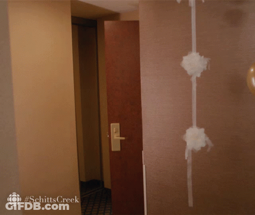 A Woman Walking Into A Room With #Schitts Creek On The Bottom Right GIF