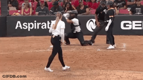 A Woman Walking On A Baseball Field In Front Of A Sign That Says Aspirational GIF
