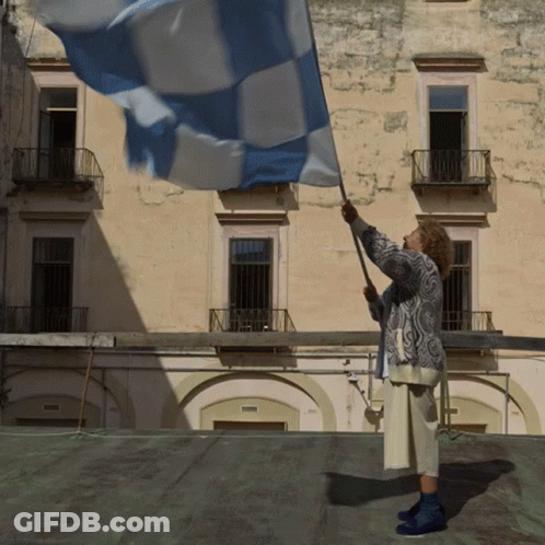 A Woman Waves A Blue And White Flag In Front Of A Building GIF