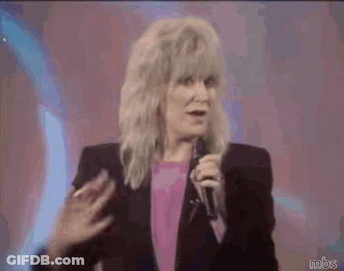 A Woman Waving Her Hand While Holding A Microphone With Mbs Written Below Her GIF