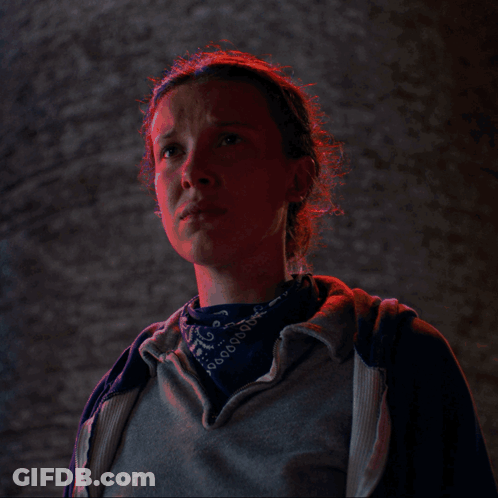 A Woman Wearing A Bandana And A Grey Hoodie Looks At The Camera GIF