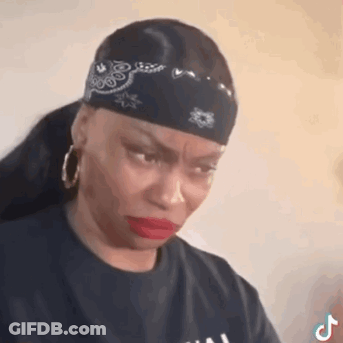 A Woman Wearing A Bandana And Earrings Is Making A Sad Face . GIF