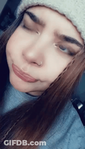 A Woman Wearing A Beanie And A Nose Ring Makes A Funny Face GIF
