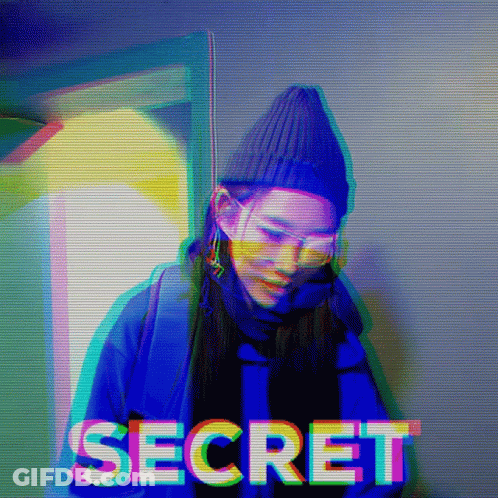 A Woman Wearing A Beanie And Sunglasses Is Standing In Front Of The Word Secret GIF