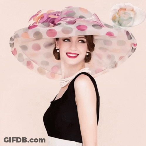 A Woman Wearing A Black And White Dress And A Polka Dot Hat GIF