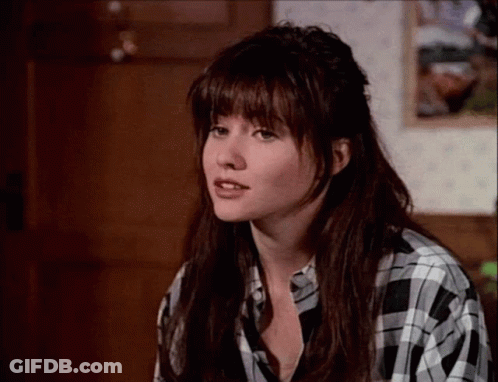A Woman Wearing A Black And White Plaid Shirt Looks At The Camera GIF