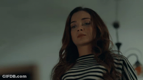 A Woman Wearing A Black And White Striped Shirt Is Looking At The Camera GIF
