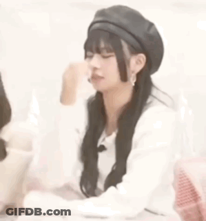 A Woman Wearing A Black Beret Is Sitting At A Table With Her Eyes Closed . GIF