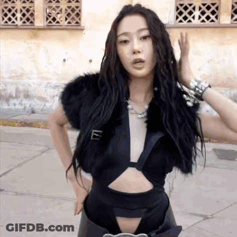 A Woman Wearing A Black Crop Top And A Fur Vest GIF