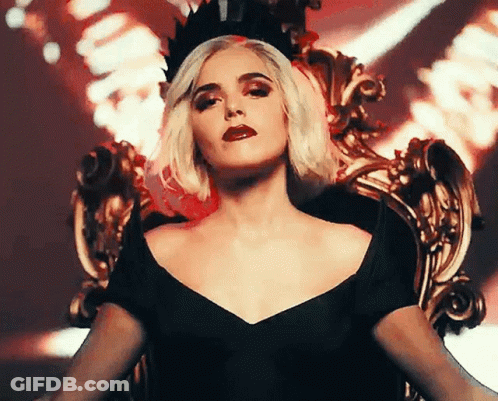 A Woman Wearing A Black Dress And A Crown Is Sitting On A Throne GIF