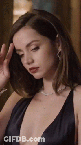A Woman Wearing A Black Dress And A Necklace With Diamonds GIF
